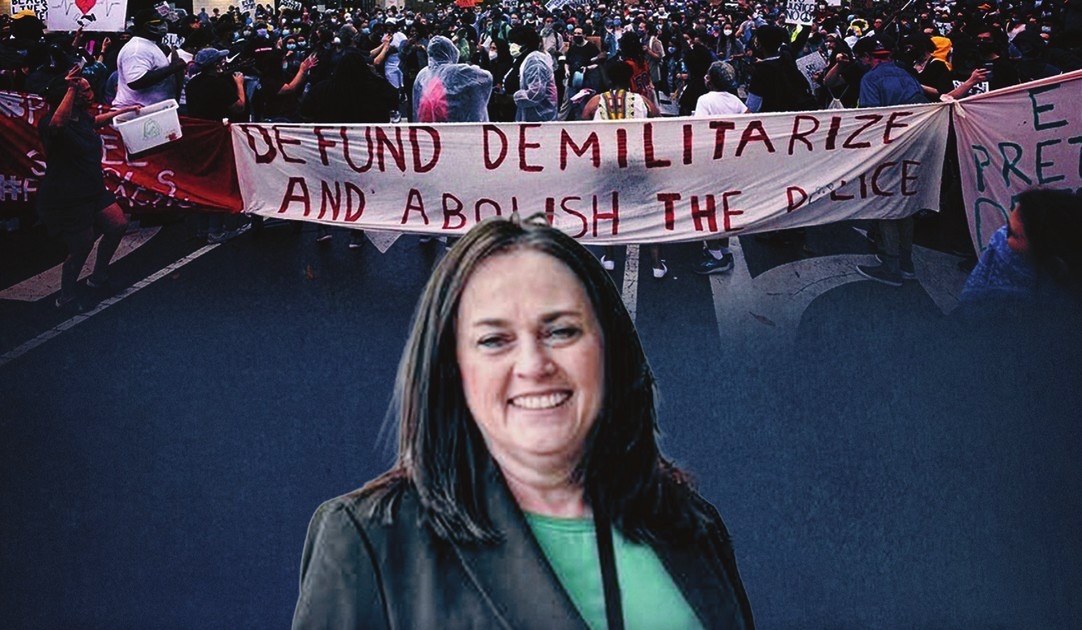 Tara Murray in front of protesters holding a “Defund, demilitarize and abolish the police” banner